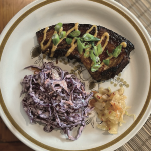 A pork chop on a plate with coleslaw and kimchi